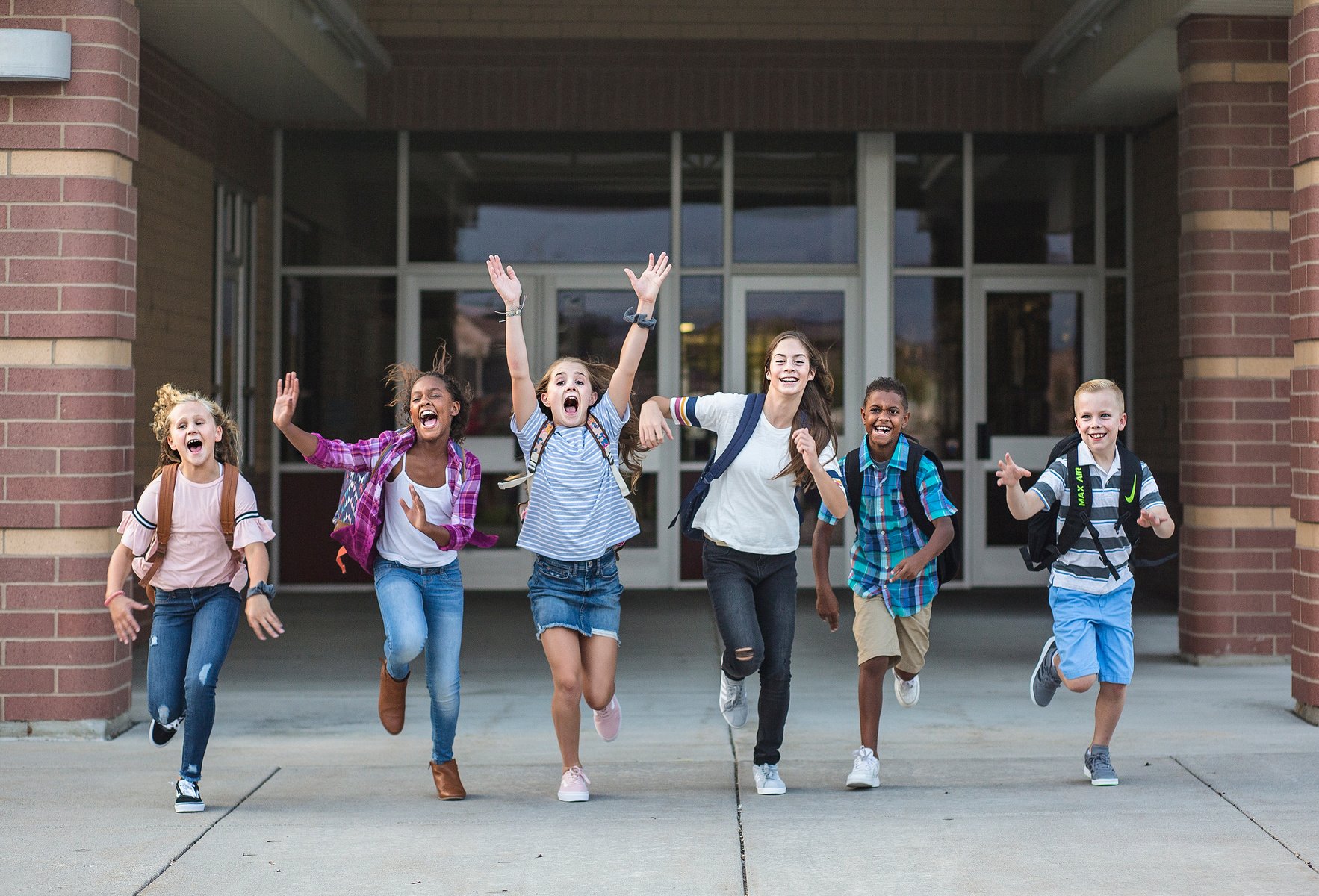 Group of school school kids running as they leave the school building