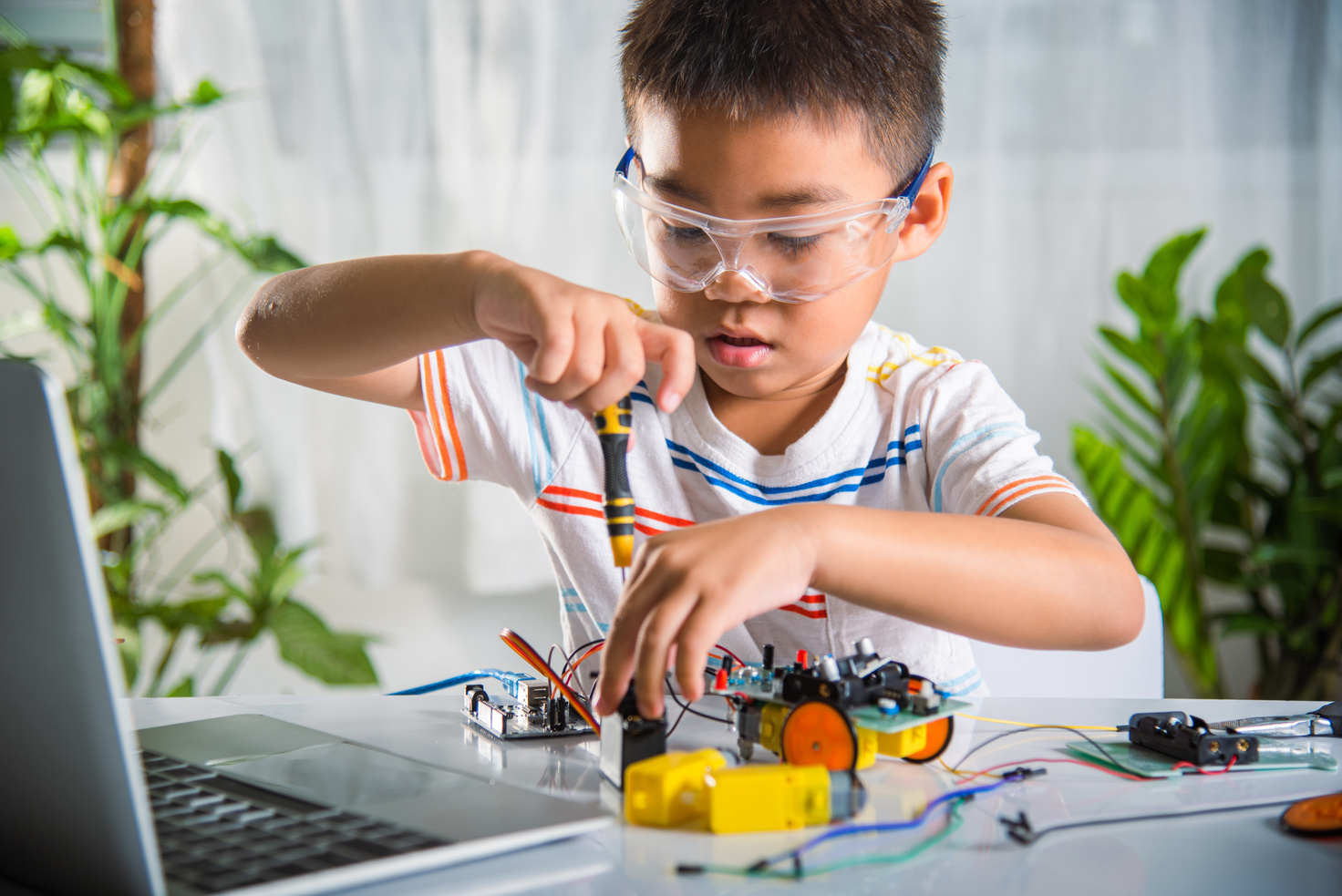 Asian kid boy assembling the Arduino robot car homework project